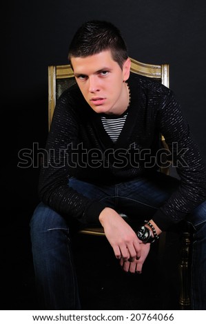 Young modern black haired man  sitting in the dark and thinking