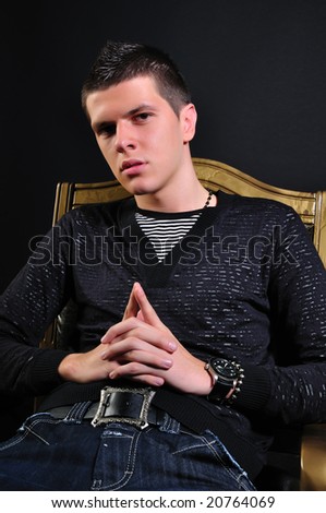 Young modern black haired man  sitting in the dark and thinking