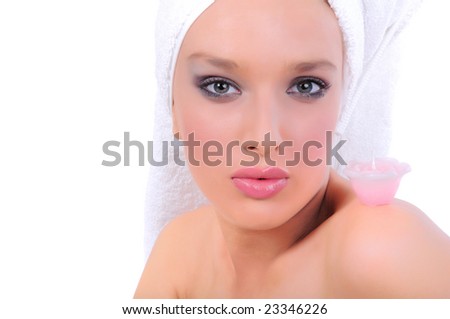 Closeup of a beautiful young woman with her head wrapped in towel with a small rose candle standing on her shoulder, isolated on white