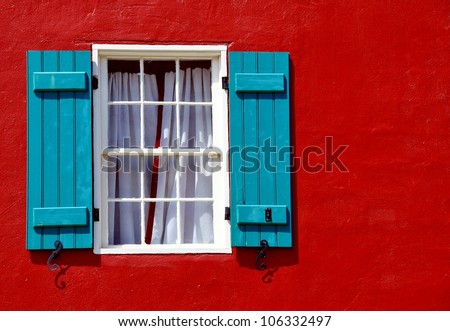 Window With Curtains And Blue Shutters On Red Stucco Exterior Wall