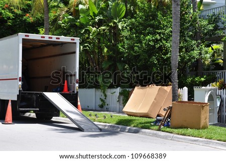 A Moving Van On Street With Ramp, Boxes And Household Furnishings