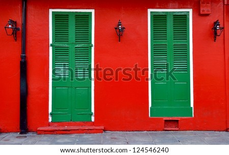 Red Exterior Wall With Green Shuttered Doors And Lanterns In New Orleans French Quarter