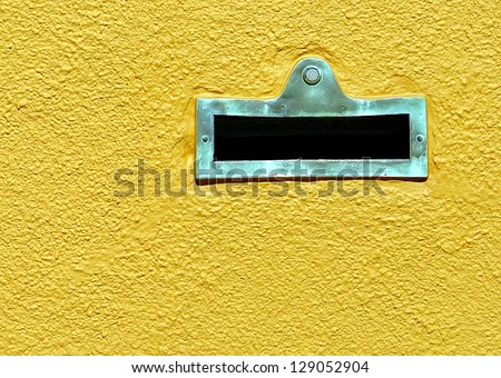 Mail Slot And Doorbell On Yellow Stucco Wall