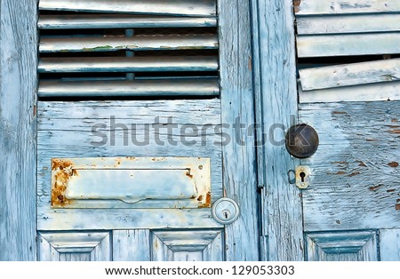 Closeup Of Old Weathered Doors With Mail Slot, Shutters, Door Knob And Keyhole Located In New Orleans French Quarter