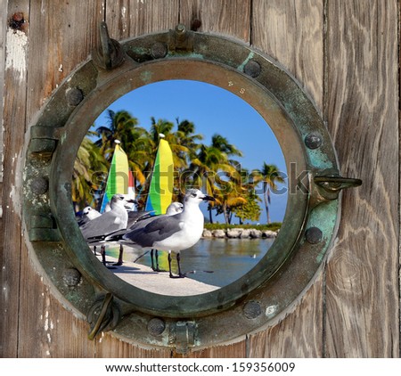Seagulls and Sailboats on Smathers Beach in Key west, Florida looking through a rustic old porthole.