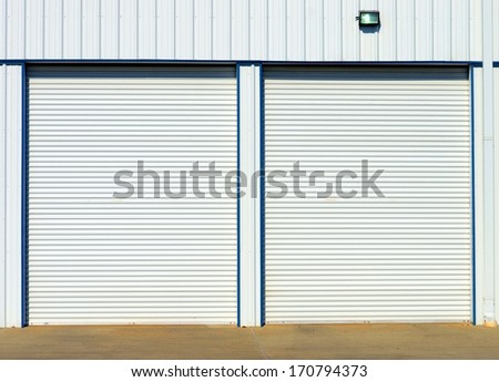 Overhead White Steel Doors At Garage Or Storage Unit With Security Light