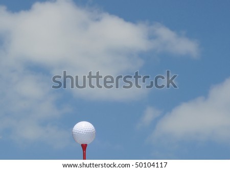 White Golf Ball On Red Tee Against Blue Sky
