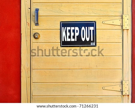 Keep Out Sign On Wooden Door In Stucco Wall