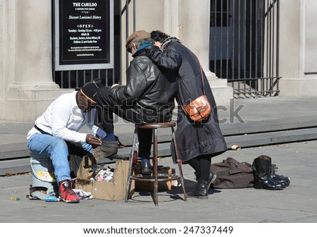 NEW ORLEANS, LA-JAN.24:  A shoe shine man  near Jackson Square in the New Orleans French Quarter polishes the shoes of a tourists in town for Mardi Gras on January 24, 2015.