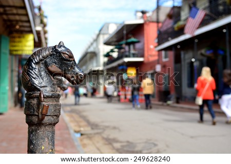 A vintage horse head hitching post on Bourbon Street in the historic New Orleans French Quarter with shallow depth of field.