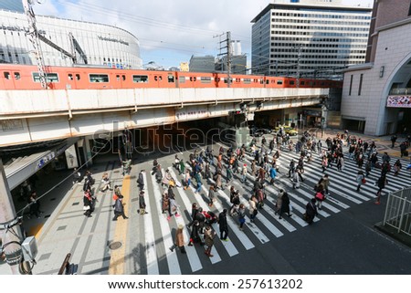 OSAKA - FEBUARY 9: People walk across the street at Osaka station on FEBUARY 9 2015 in Osaka. It is a city in the Kansai region of Japan\'s main island of Honshu
