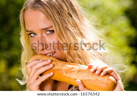 Smiling blond young woman biting white bread