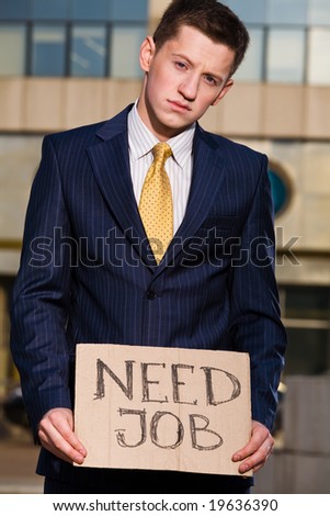 Financial crisis. Unemployment. Young businessman holding sign Need Job outdoors