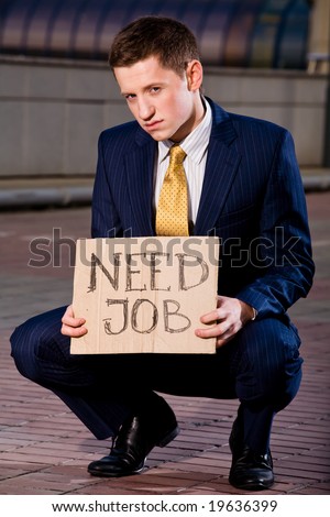 Financial crisis. Unemployment. Young businessman squatting with sign Need Job outdoors