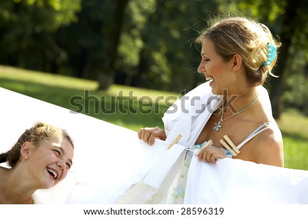 Funny mom and daughter hanging clothes on the line outdoors