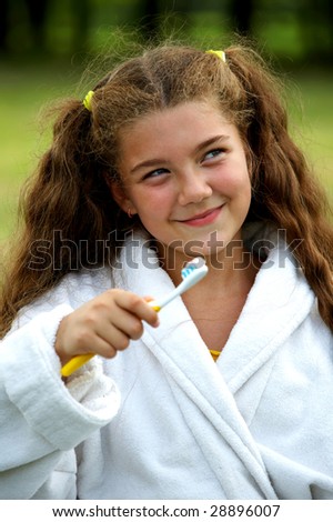 Funny little cute girl brushing teeth outdoors