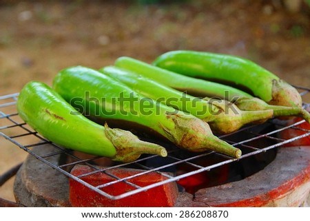 Grilling eggplants on earthen stove, old style Asian cooking/Fresh eggplants on old style stove