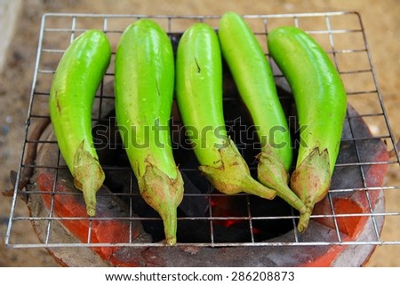Green eggplants on earthen stove, old style Asian cooking