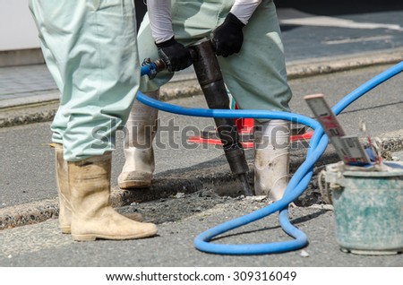 Road repairing work using jackhammer drilling asphalt road