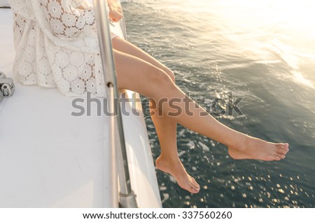 Female legs outside of yacht under warm sunset flare