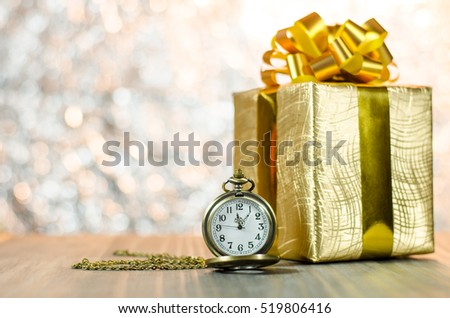 Vintage pocket watch with gold christmas gift box, ribbon and bow on bokeh lights background