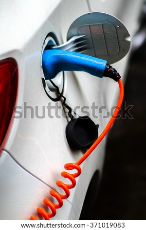 Green car is charging on its voltage supplier.