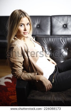 blond woman in leather jacket, blonde woman sitting on couch, leather couch