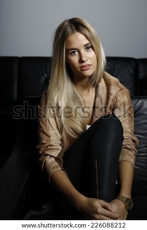 blond woman in leather jacket, blonde woman sitting on couch, leather couch
