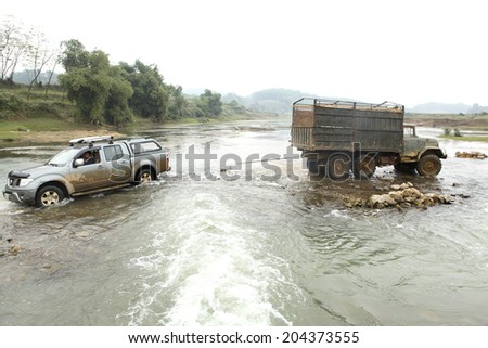 HOA BINH, VIET NAM - DEC 28, 2012: The car (Zil truck) pulls a broken car with a rope crossing a river at Hoabinh, Vietnam