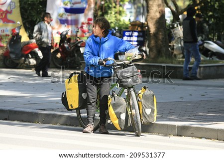 HA NOI, VIET NAM - DECEMBER 19, 2013: Bicycle tourist with his loaded bike standing on a street in Hanoi, Vietnam