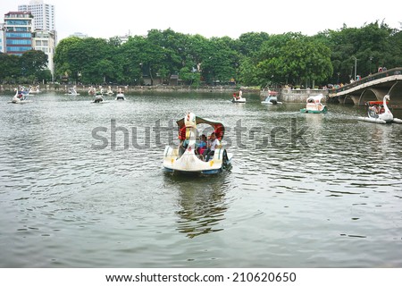 HA NOI, VIET NAM - JULY 13, 2014: Unidentified Vietnamese children paddling a swan boat on the lake of Thu Le park, Hanoi capital. The park also has a zoo.