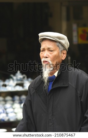HA NOI, VIET NAM - NOV 20, 2008 :An Vietnamese old man portrait (name unknown) and long white beard was standing alone in Bat Trang market (ceramic market) in Vietnam