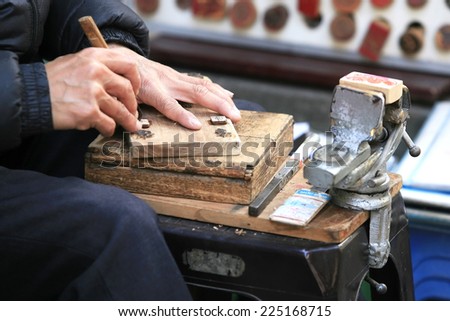 Ha Noi, Viet Nam - Dec 19, 2013: Vietnamese craftsman carving a wooden seal in Hanoi. They do stamp service for tourist