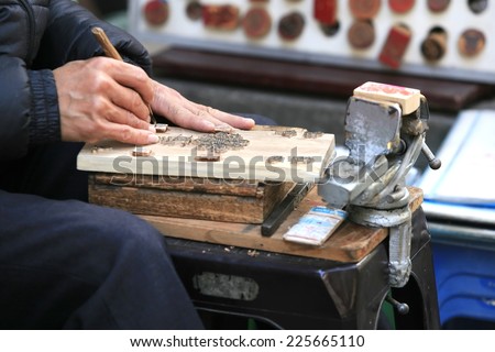 Ha Noi, Viet Nam - Dec 19, 2013: Vietnamese craftsman carving a wooden seal in Hanoi. They do stamp service for tourist