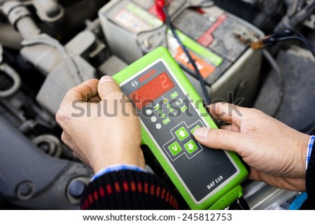 Ha Noi, Viet Nam - Dec 13, 2014: Auto mechanic uses multimeter voltmeter to check voltage level in car battery in Vietnam