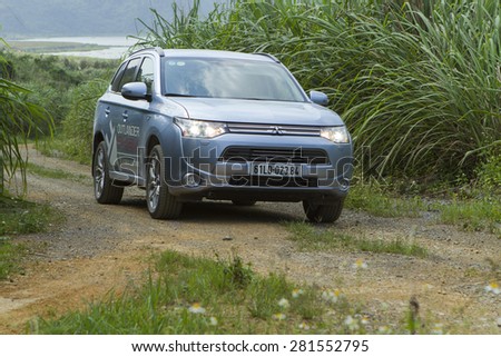 Ha Noi, Viet Nam - May 18, 2015: The Mitsubishi Outlander PHEV plug-in Hybrid CUV car  running on the dirt road in Vietnam