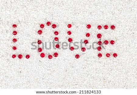 the inscription Love red crystal on a white coarse sand