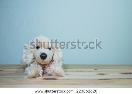 toy dog doll on wooden table over grunge background