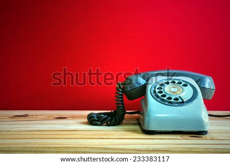 Still life with retro phone on wooden table over red grunge background