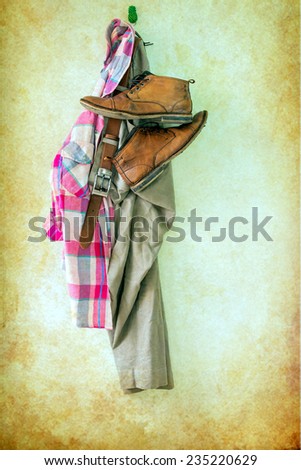 Brown pants,plaid shirt and boots hanging over grunge background