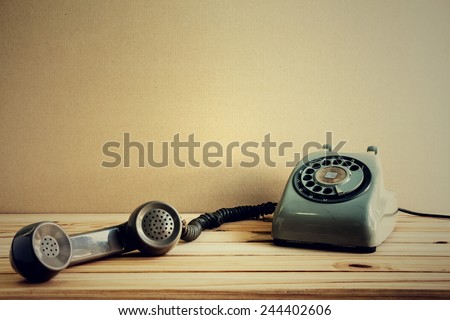 Still life with retro phone on wooden table over grunge background