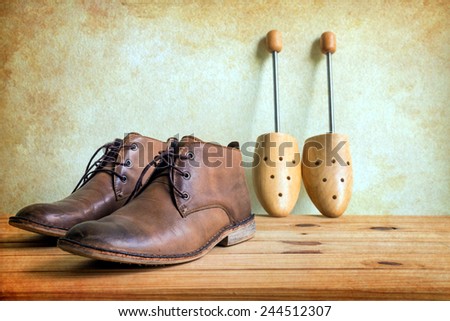 Still life with boots and wooden shoe tree on wooden table over grunge background