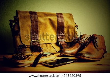 Still life with casual man, boots and bag on wooden table over grunge background