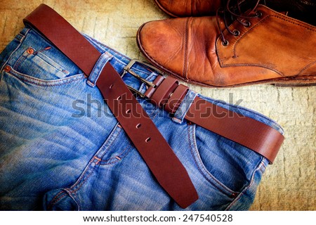 Still life with jeans and boots on green carpet background