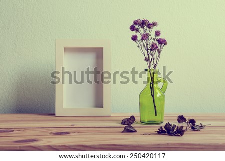 Still life with flowers and white photo frame on wooden table over grunge background, Valentine concept