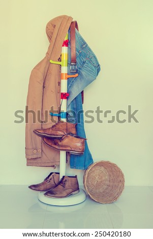 still life with plaid shirt, jeans and boots hanging over grunge background, casual vintage style.