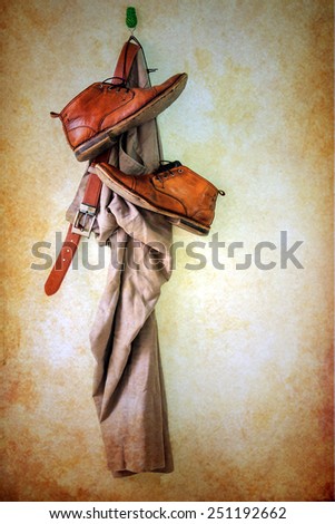 Still life with brown pants and boots hanging over grunge background