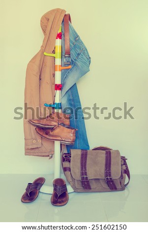 still life with overcoat, jeans and boots hanging over grunge background, casual vintage style.