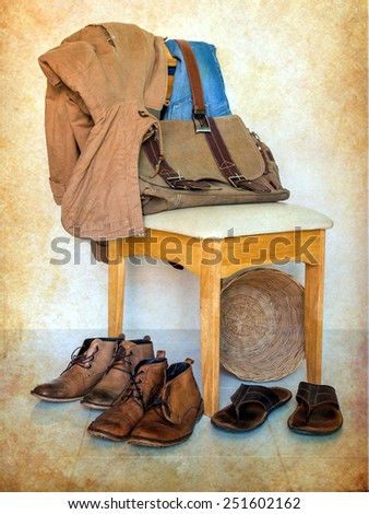 still life with overcoat, boots, bag and jeans on wooden chair over grunge background ,casual vintage style.