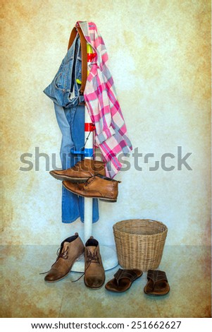 still life with plaid shirt, jeans and boots hanging over grunge background, casual vintage style.
